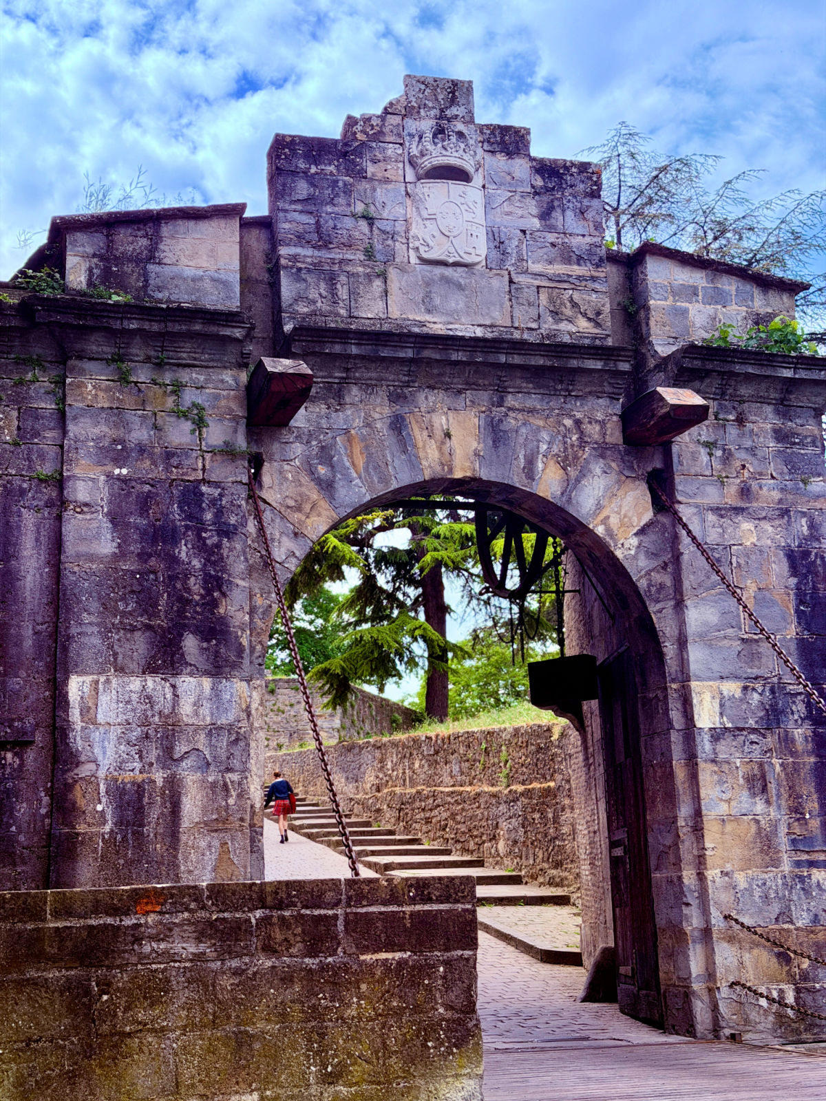 Historic stone gateway and drawbridge entrance through the fortified walls of Pamplona.
