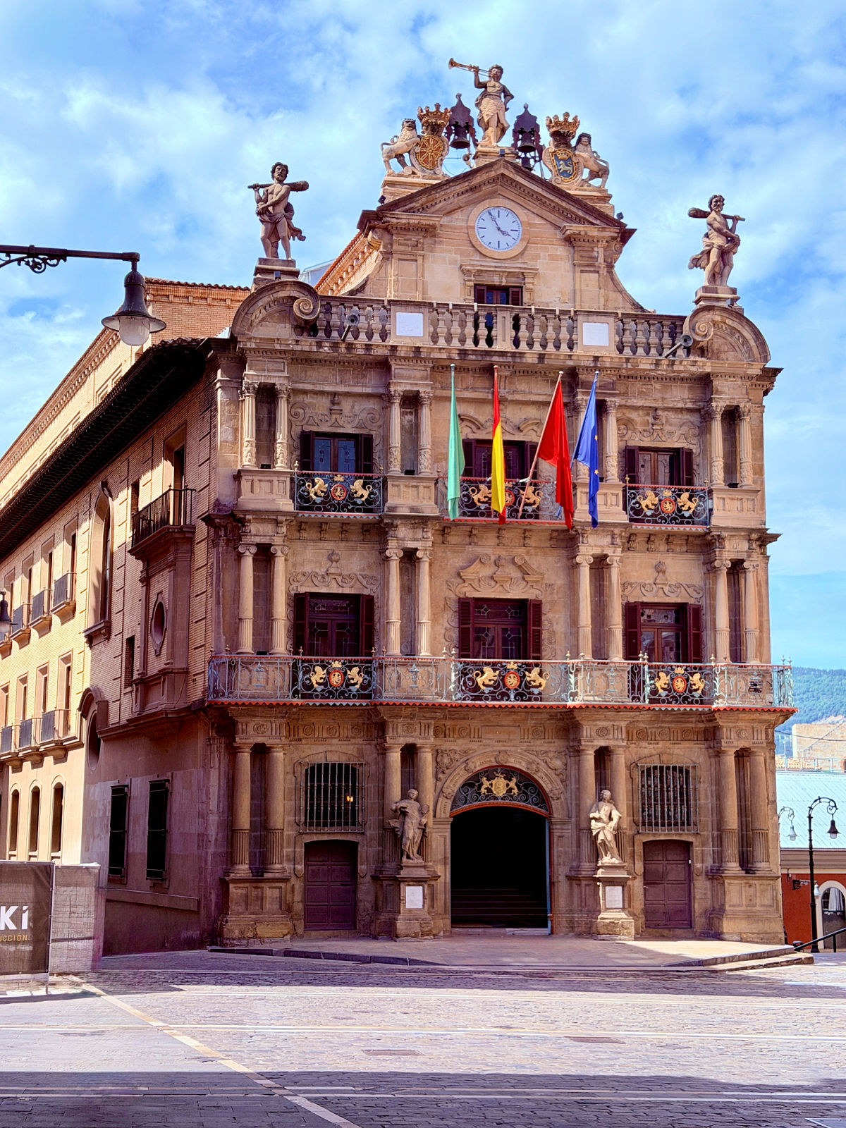 Ornate Baroque façade of Pamplona City Hall with statues, flags, and a central clock.