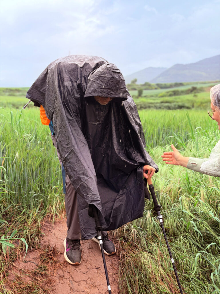 One Camino pilgrim helping another getting down an embankment along the Camino.