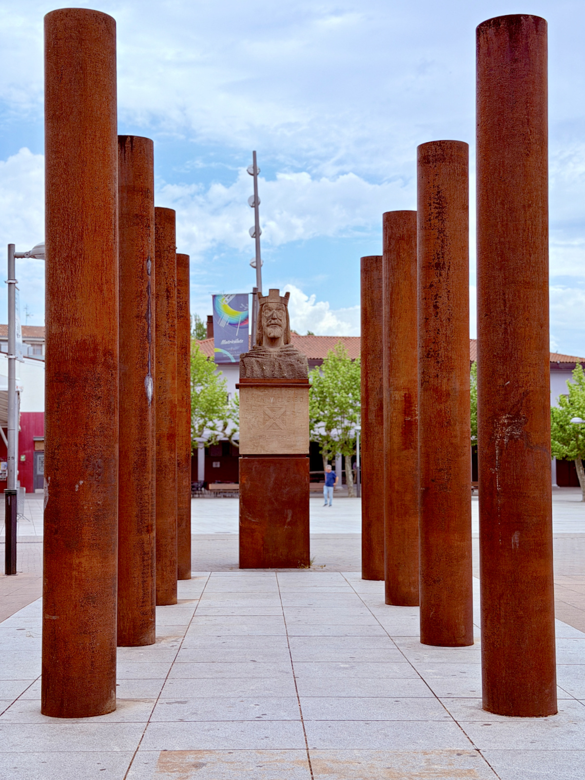 Monument to King Sancho VI the Wise surrounded by tall rust-colored columns in Pamplona, Spain.