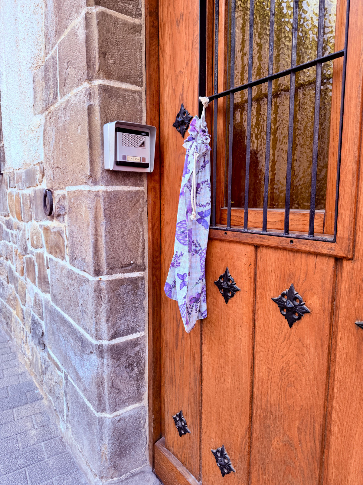 Reusable cloth bread bag hanging from the wooden front door of a home in Spain.