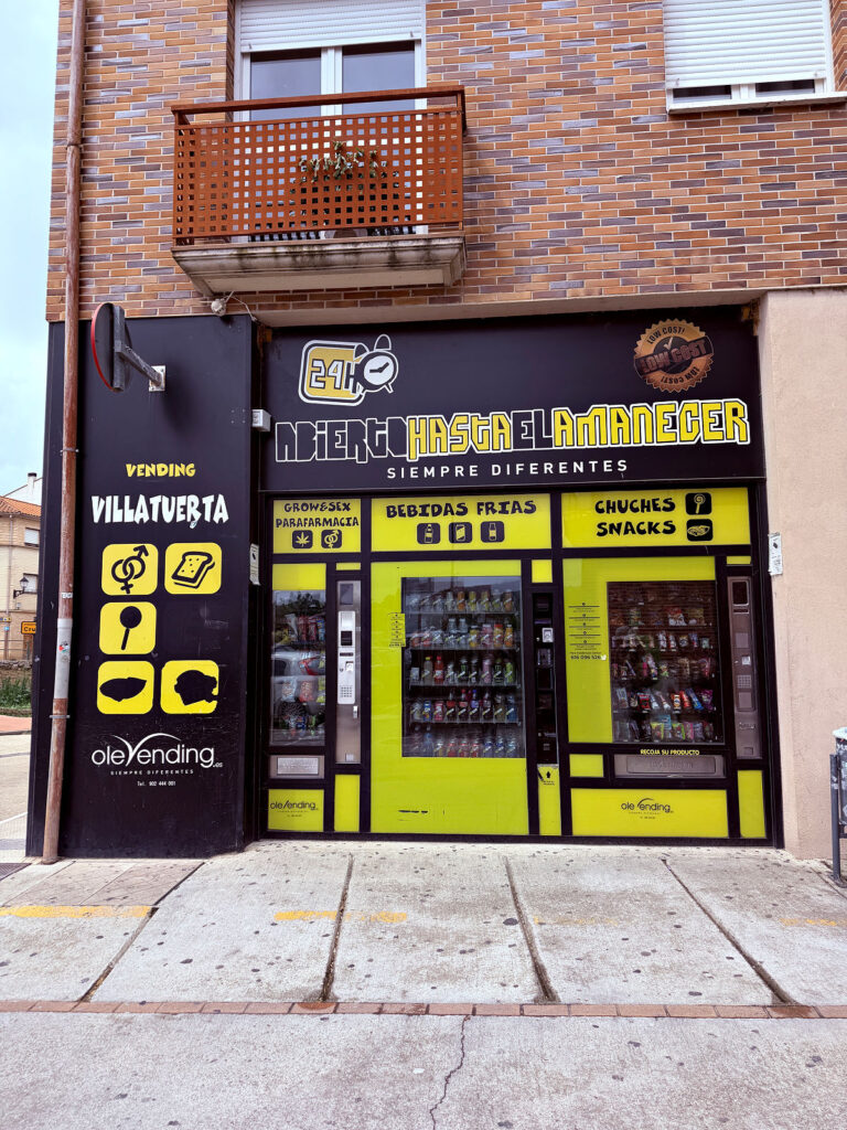 Bright yellow self-service vending machines built into a storefront in Spain.