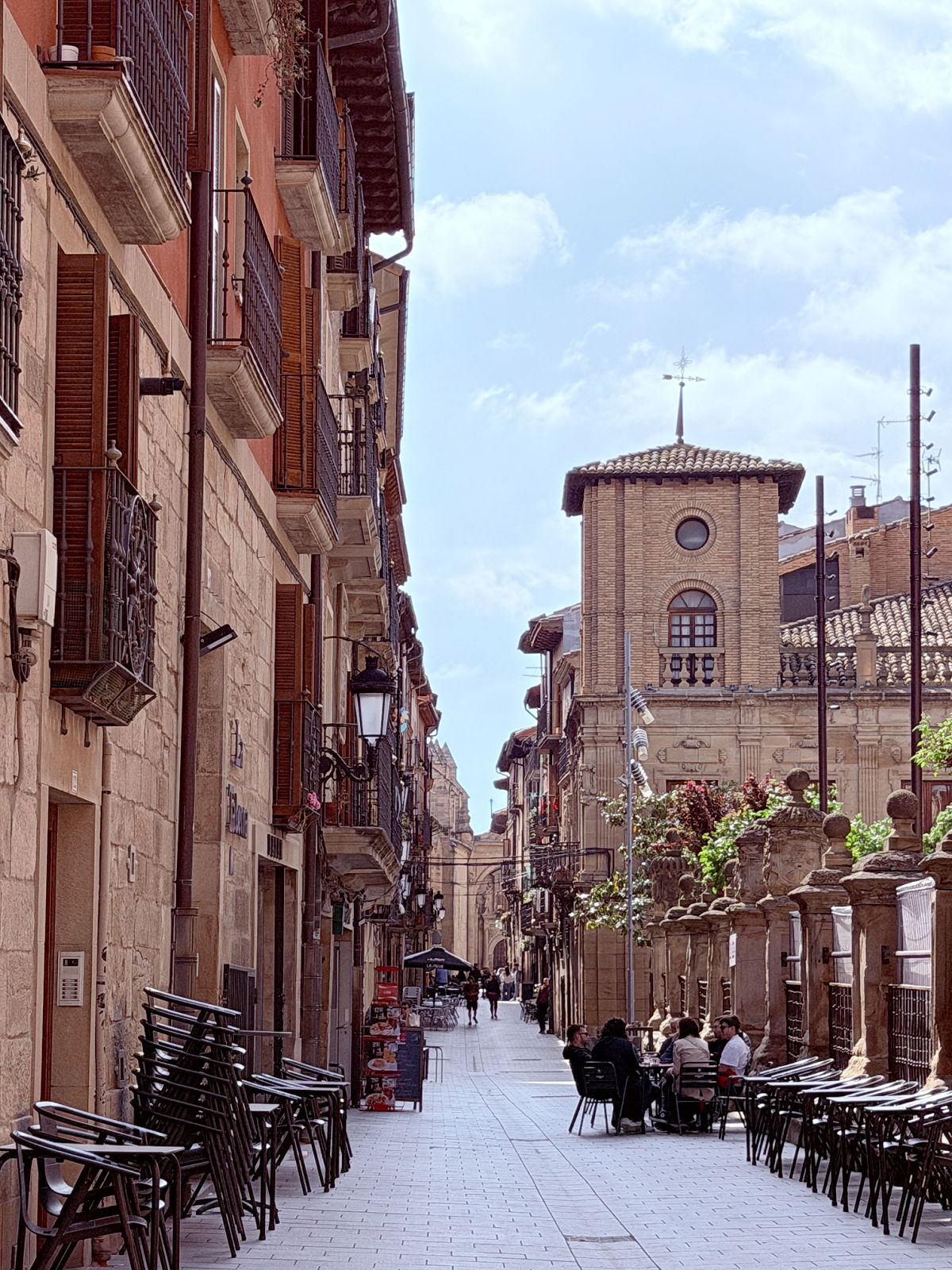 Pedestrian street lined with historic buildings and outdoor café tables in Viana, Spain.