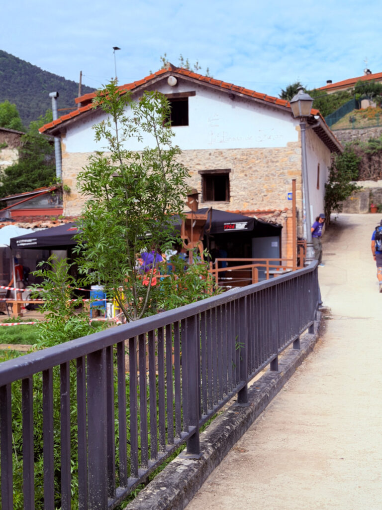 Camino pilgrims pass La Parada de Zuriain beside a bridge in Zuriain, Spain.