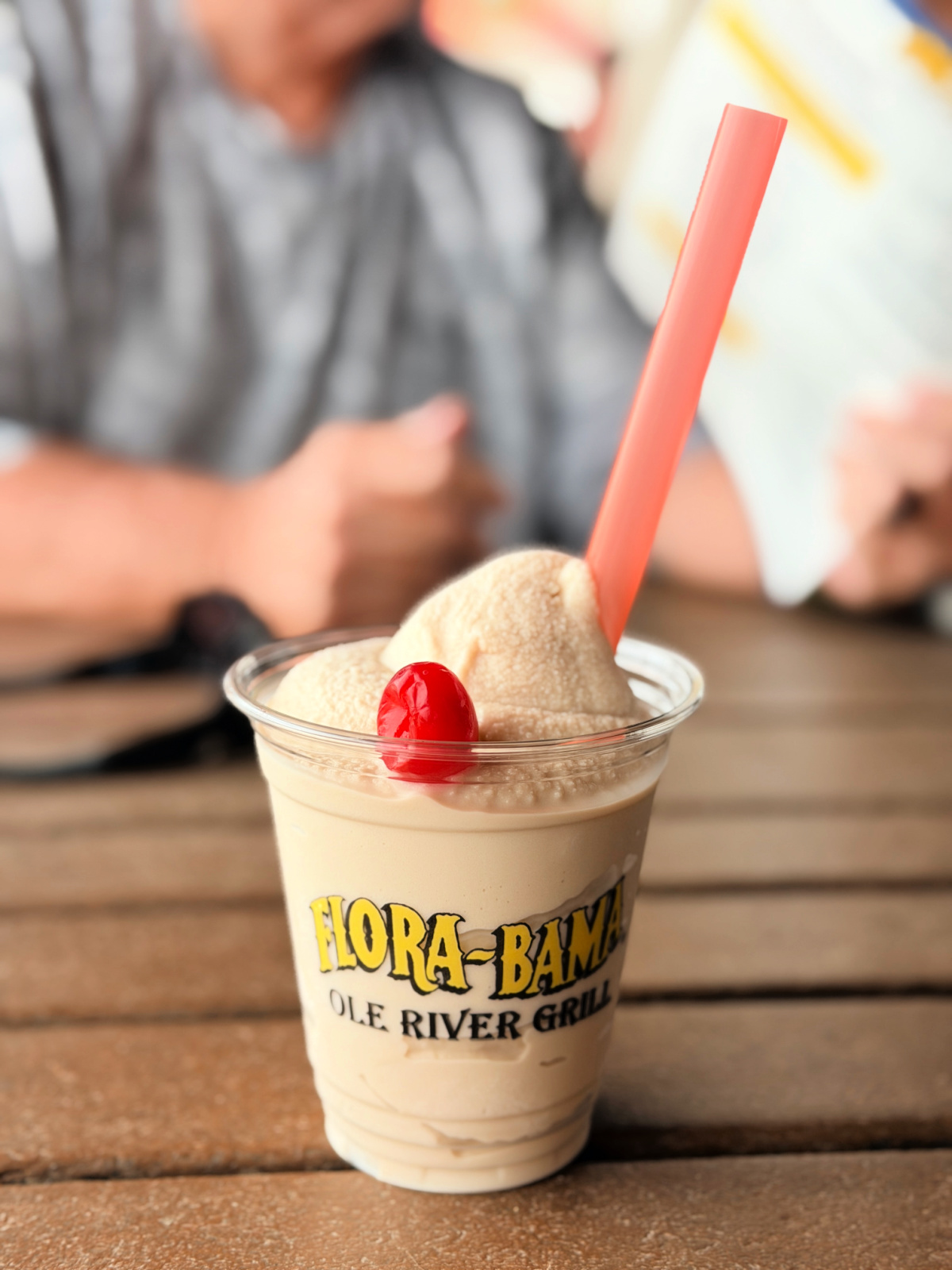Frozen Bushwacker topped with a cherry in a Flora-Bama cup with a pink straw.