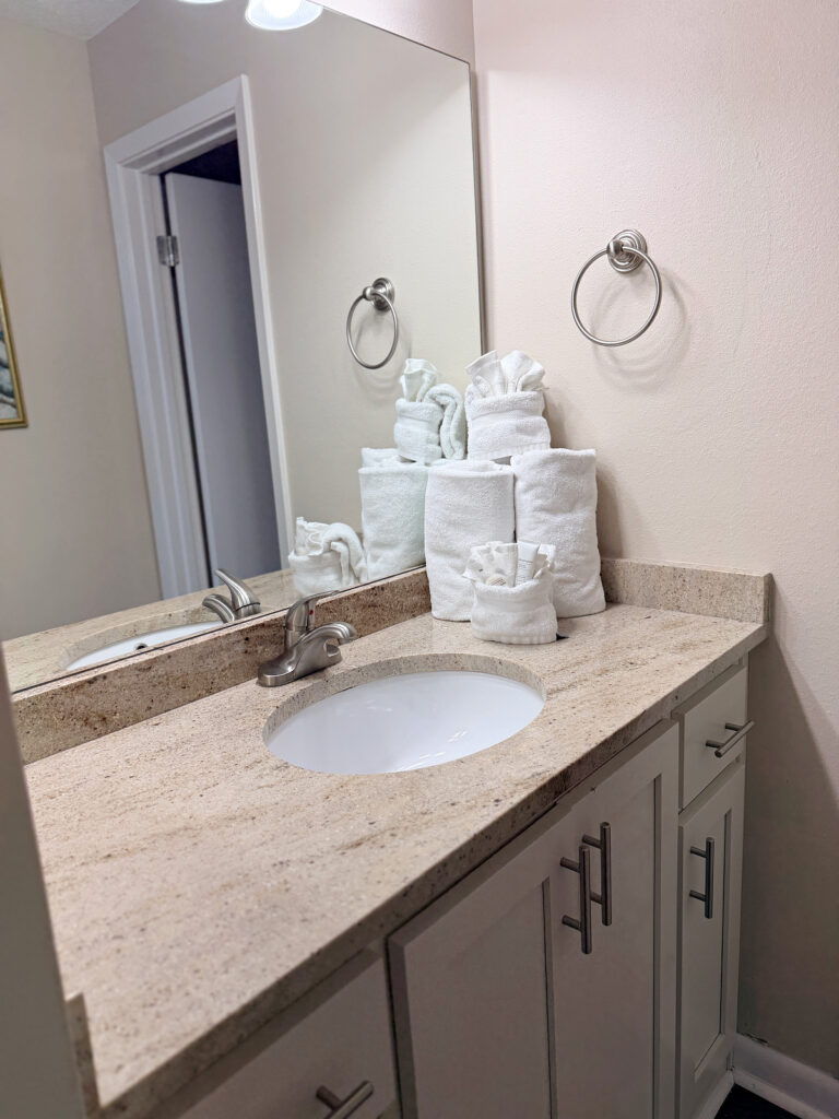 Bathroom vanity with a granite countertop and rolled white towels.