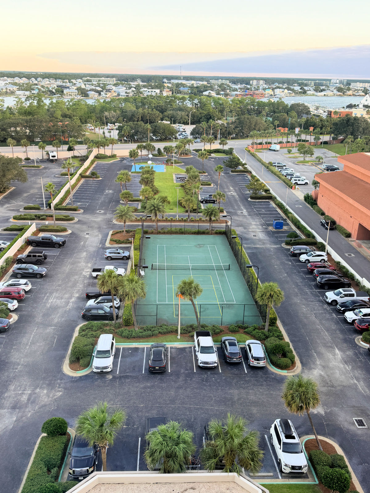 View from a Phoenix East II balcony of the parking lot, tennis court, and Perdido Beach Boulevard, with the bay beyond.