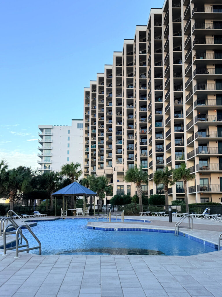 Outdoor pool with a gazebo in front of a tall Phoenix condo tower in Orange Beach.