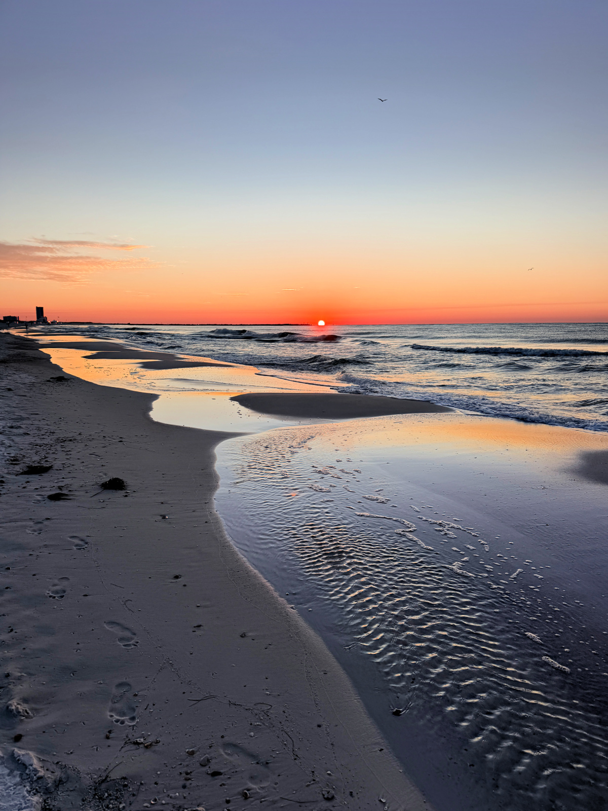 Sunrise over the Gulf of Mexico reflected in the wet sand along the beach in Orange Beach, Alabama.